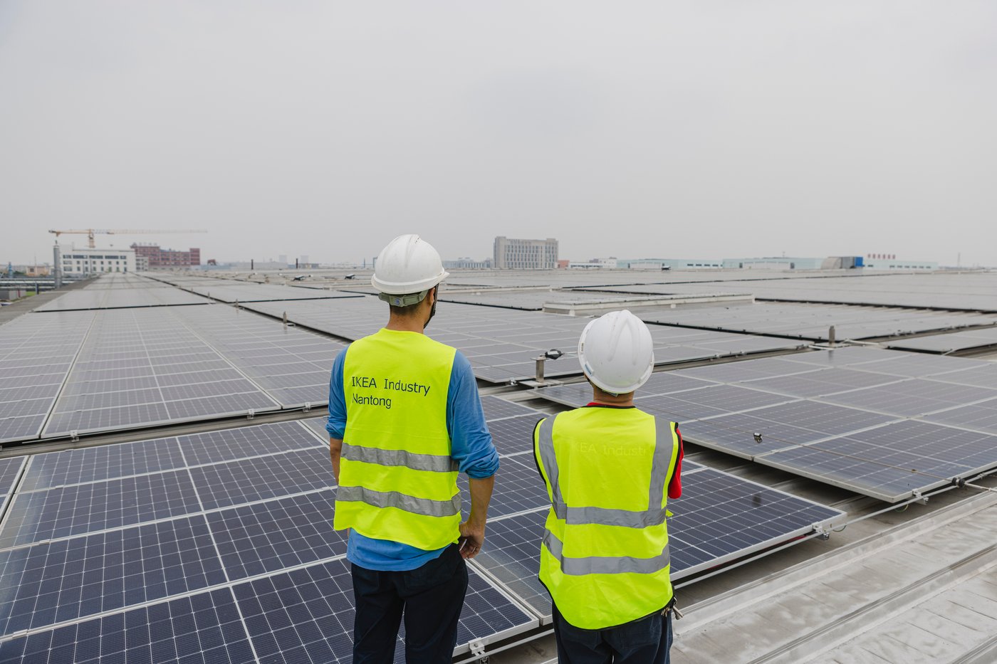 Two people look out over solar panels at the Nantong factory.