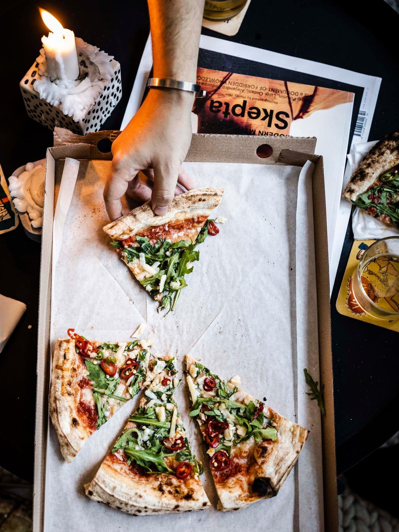 A hand grabs a slice of pizza from a pizza box.