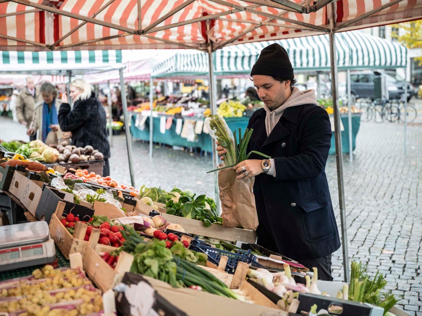 Linus buys fresh vegetables at an outdoor produce market.