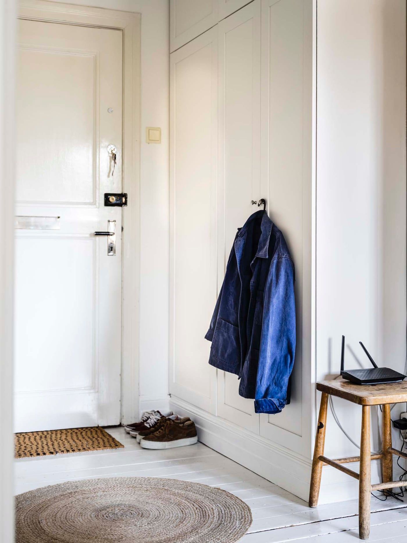 A blue jacket hangs from the door of a wardrobe in a small hallway.
