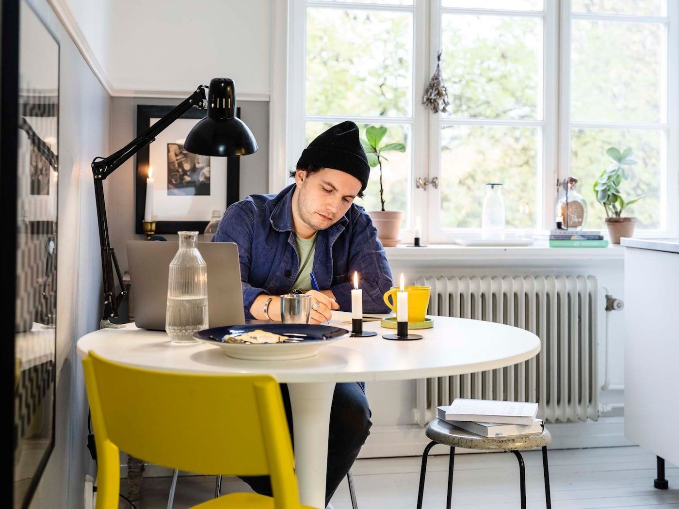 Linus sits at a small round table, writing notes in a workbook.