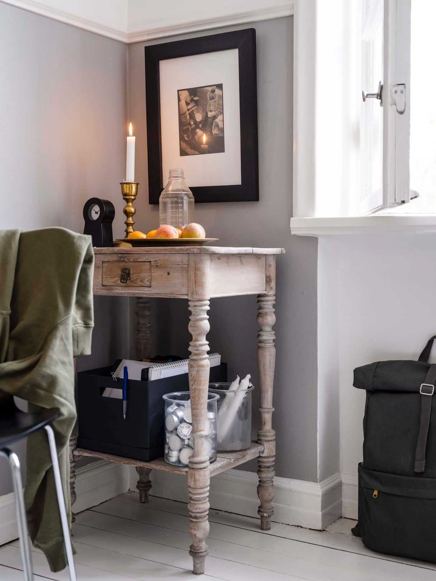 A small vintage side table holds candles and a box of study supplies.