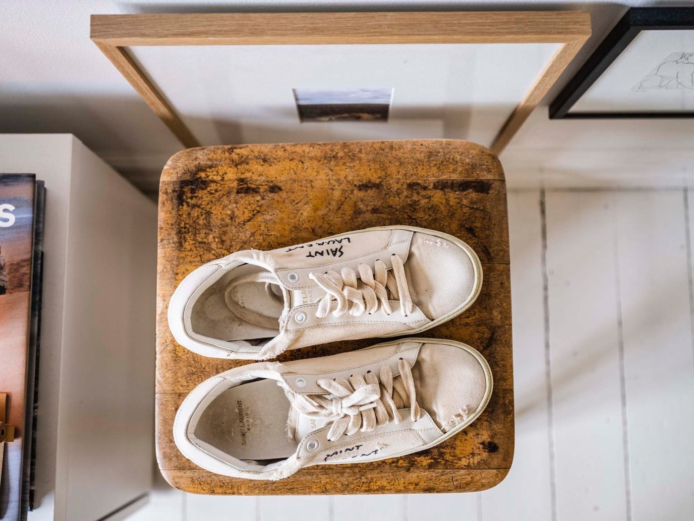Top-down view of white sneakers on a wooden stool.