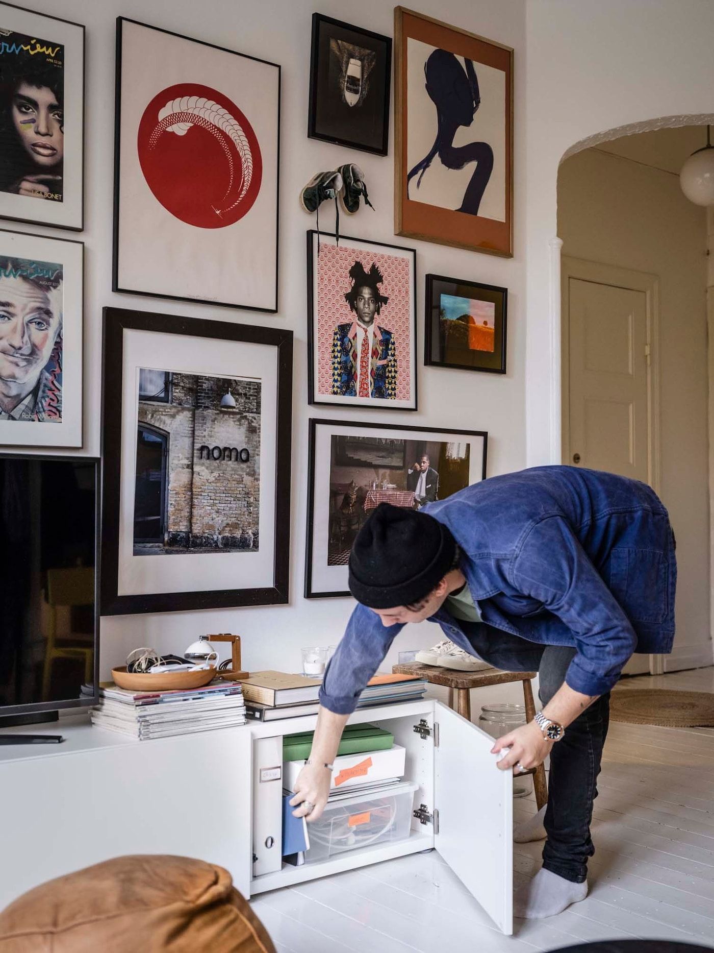 Linus leans over to grab something from inside his living room's TV bench.