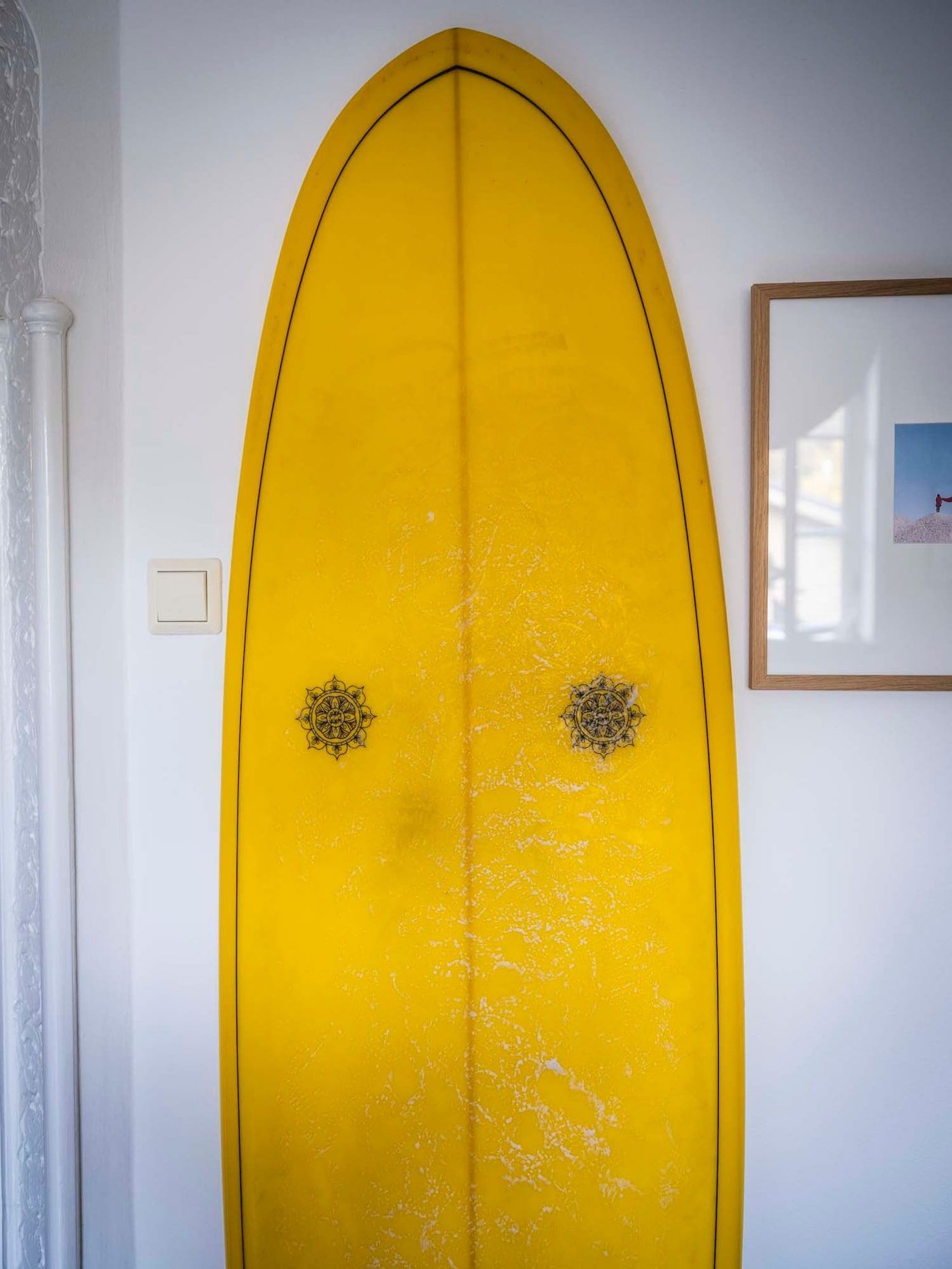 A yellow surfboard propped up against a wall.