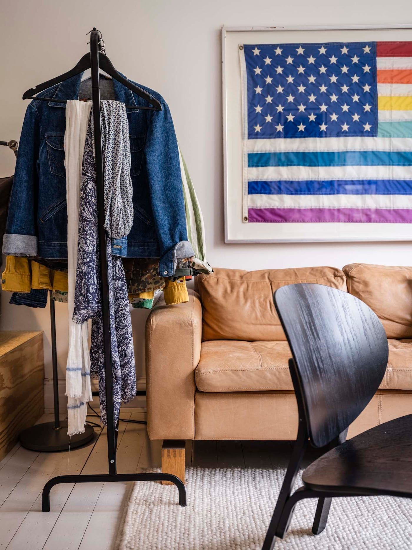 A clothing rail directly beside a leather sofa in a living room.