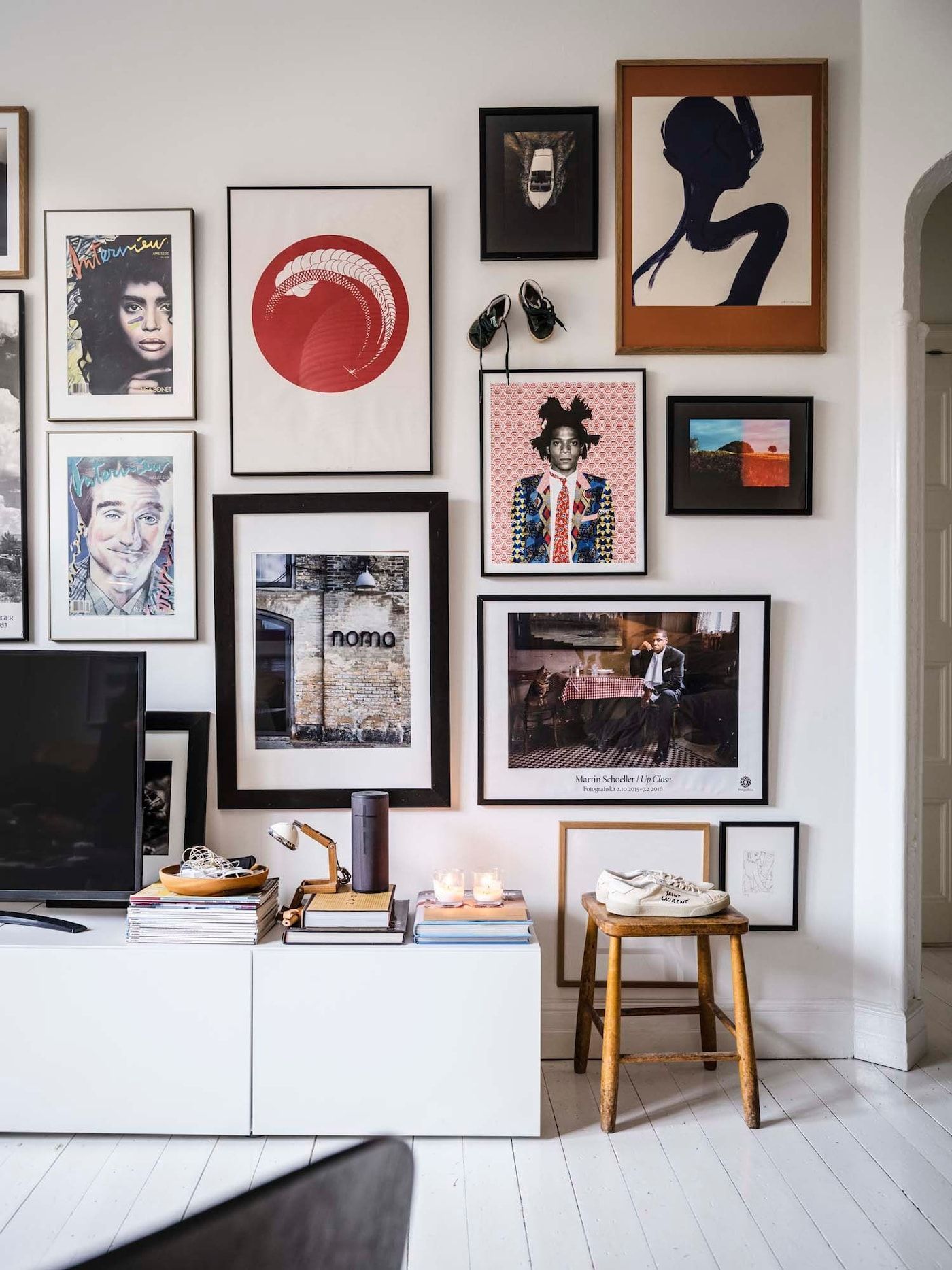 A gallery wall of photos and posters above a TV bench.