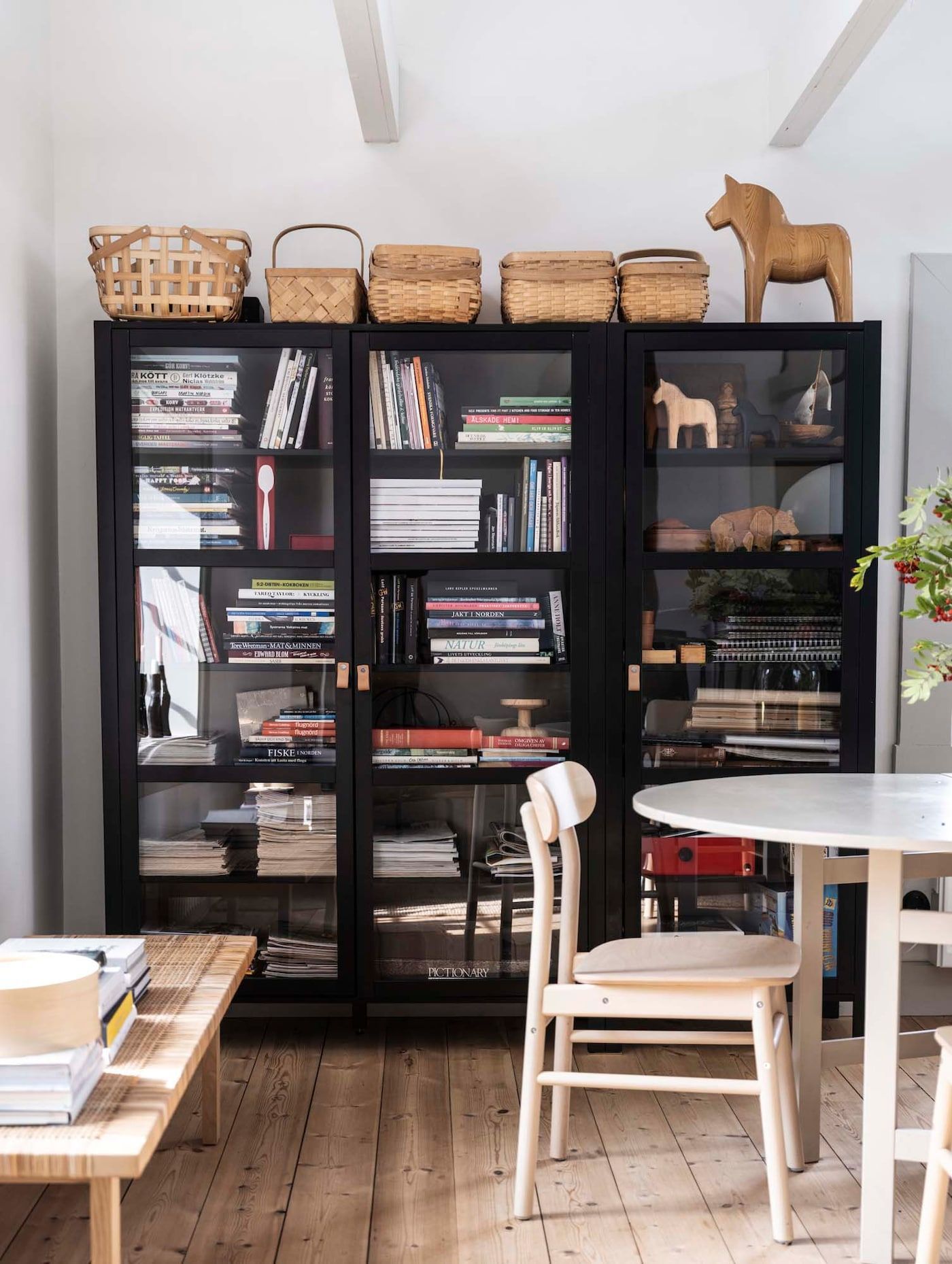 A large, black bookcase with glass doors against a wall behind a dining area.