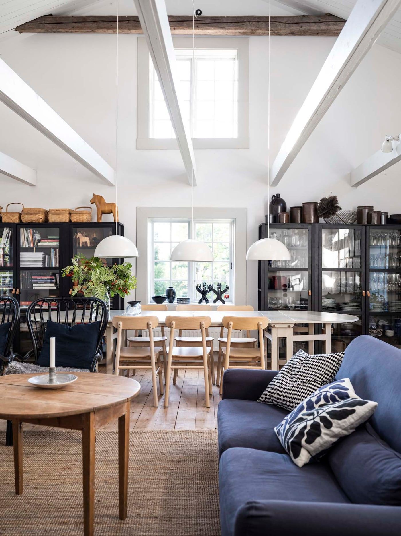 A spacious living and dining room with tall ceilings and exposed beams.