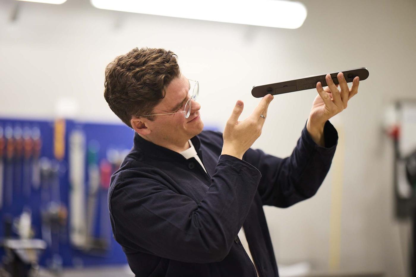 Designer Lukas Bazle holds up a strip light and inspects it.