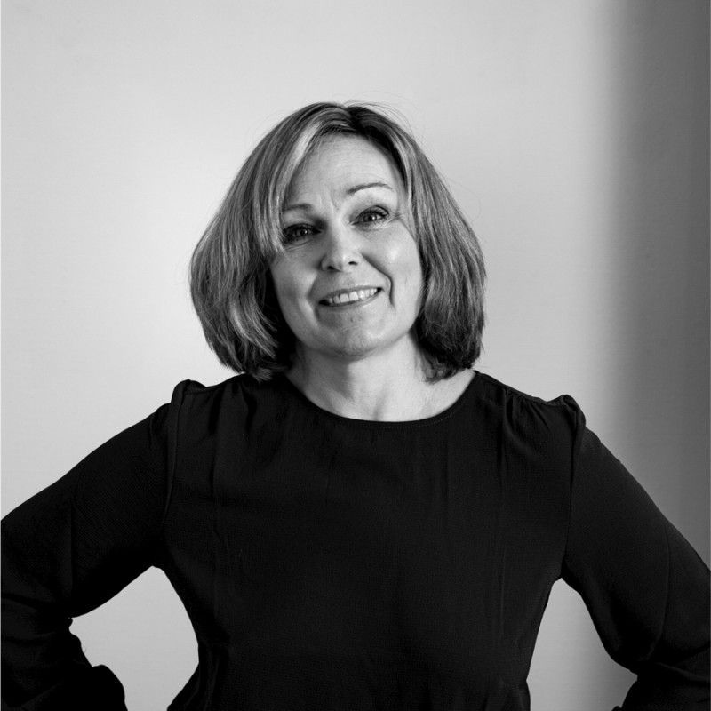 A black and white image of Marie Olsson smiling at the camera. She is wearing a dark top.