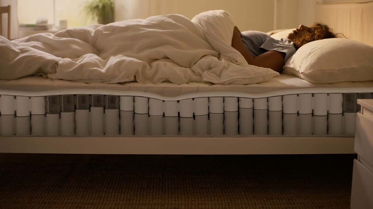 A person in bed. The side of the mattress reveals the inner springs.