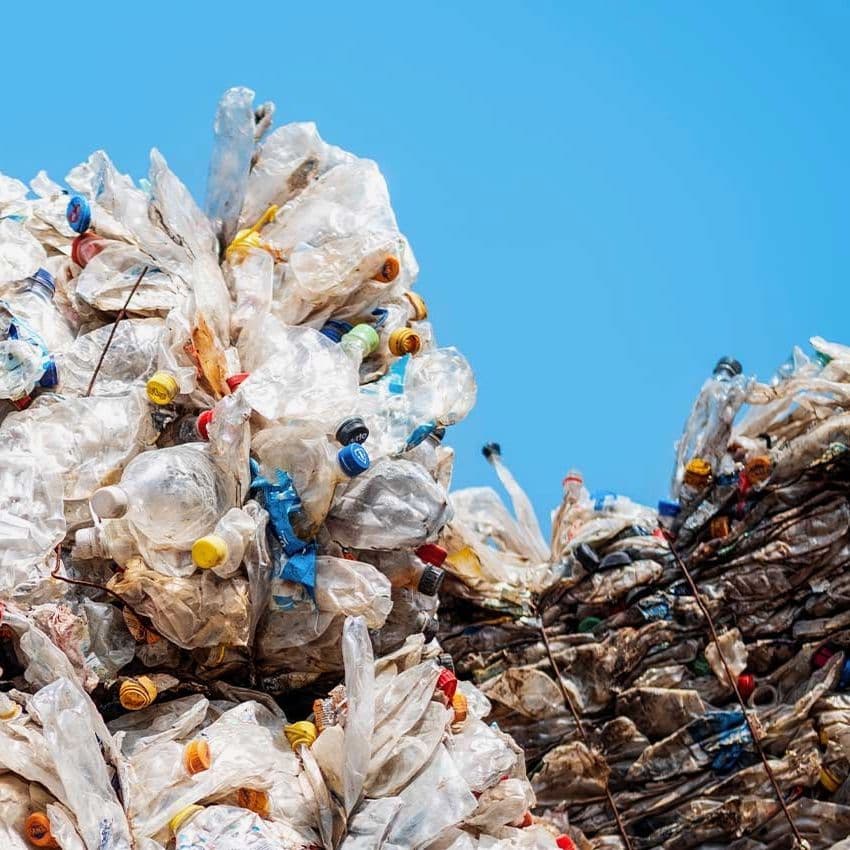 Two large piles of plastic waste in front of a clear, blue sky.