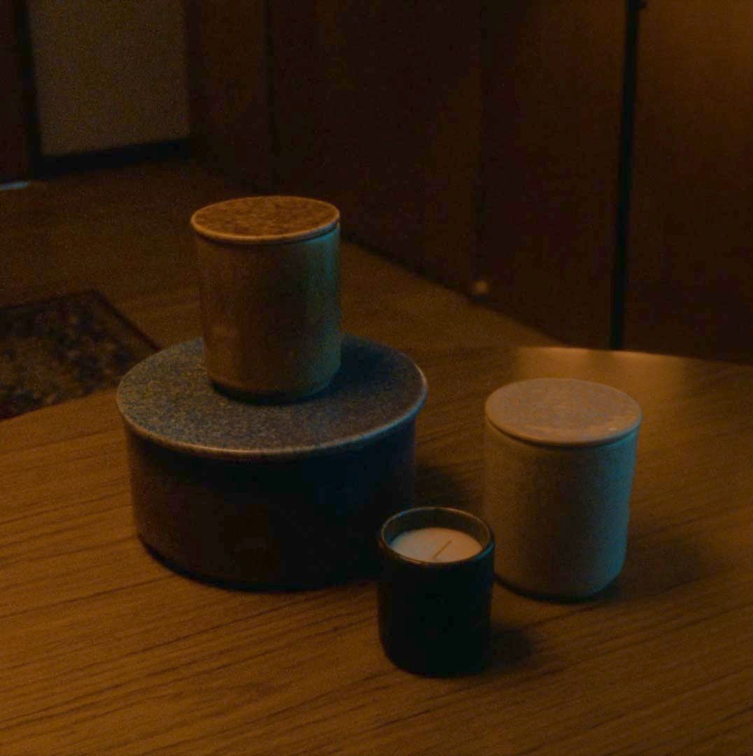 A candle sits on a wood table in a dark room. The light flashes from time to time.