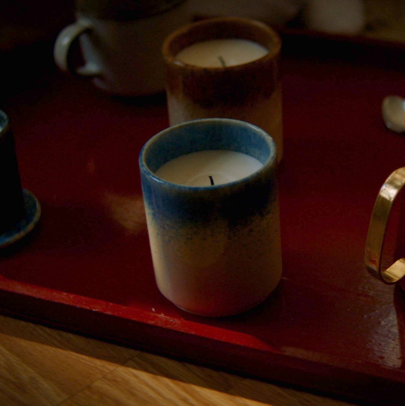 A person lights a candle on a tray.
