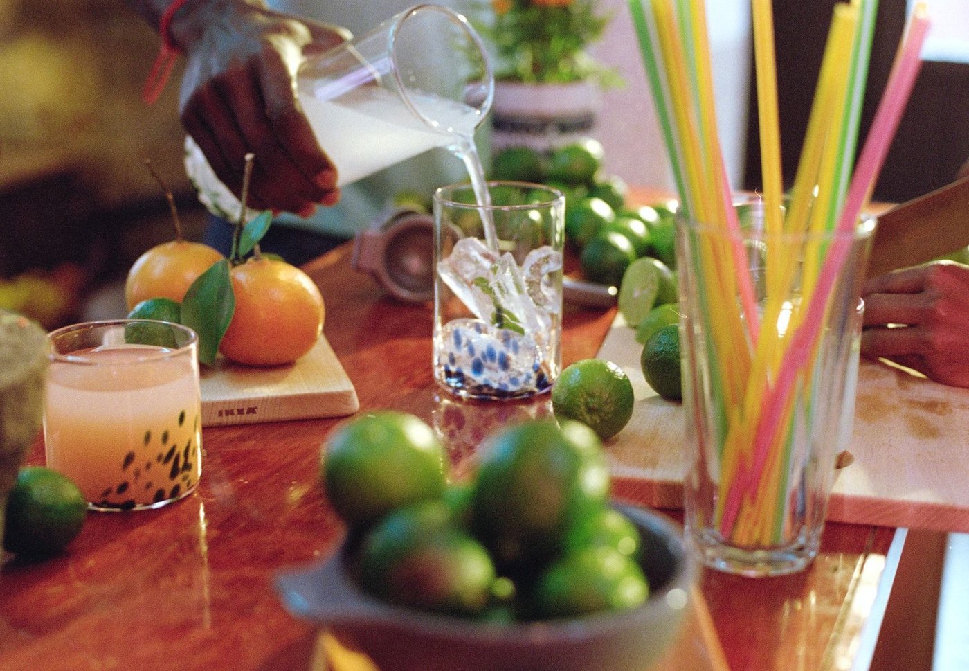 Citrus fruits, colourful straws and glassware from the ÖMSESIDIG collection on a table.