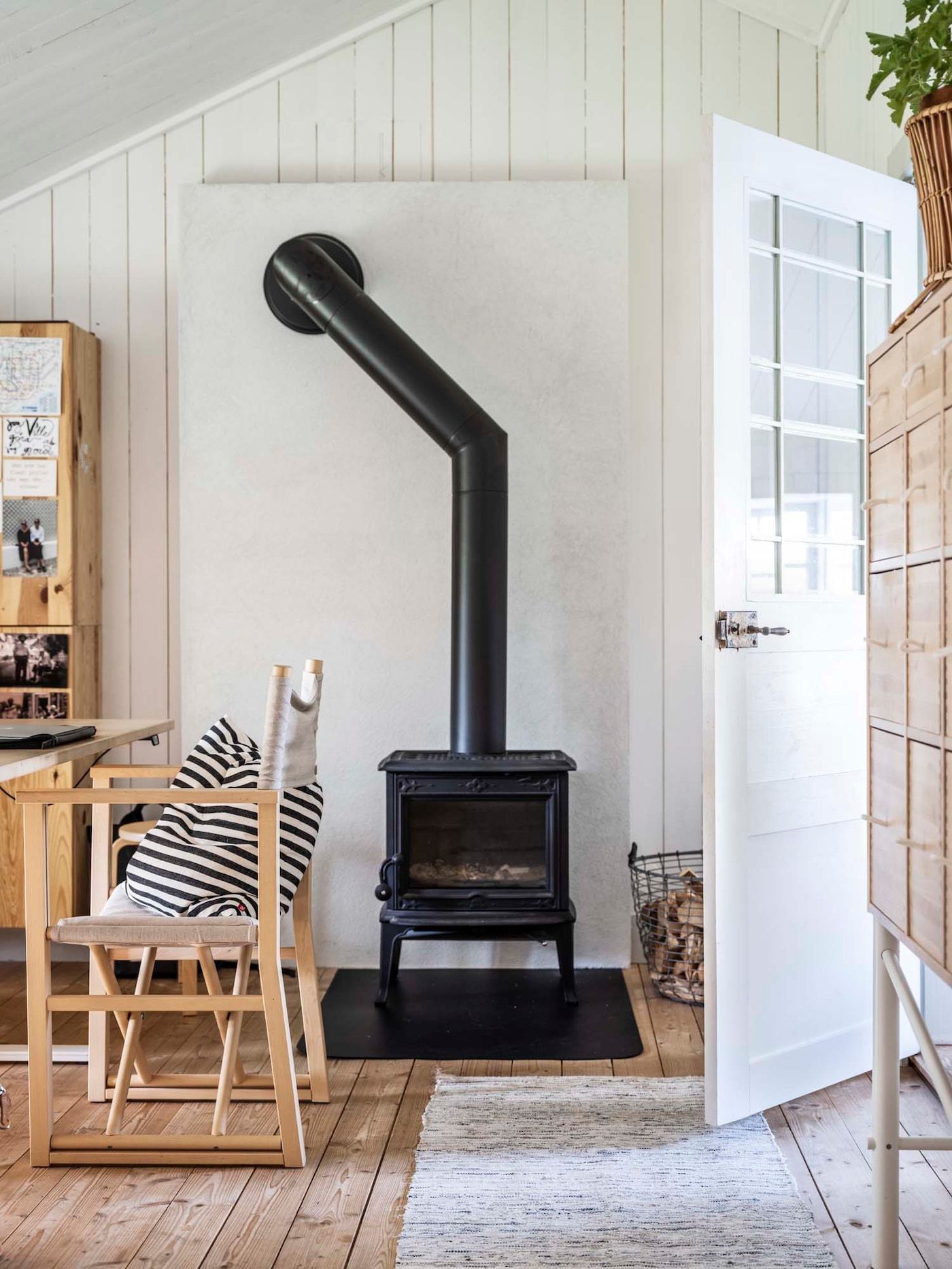 A white walled home office with light wood furniture and black fireplace.