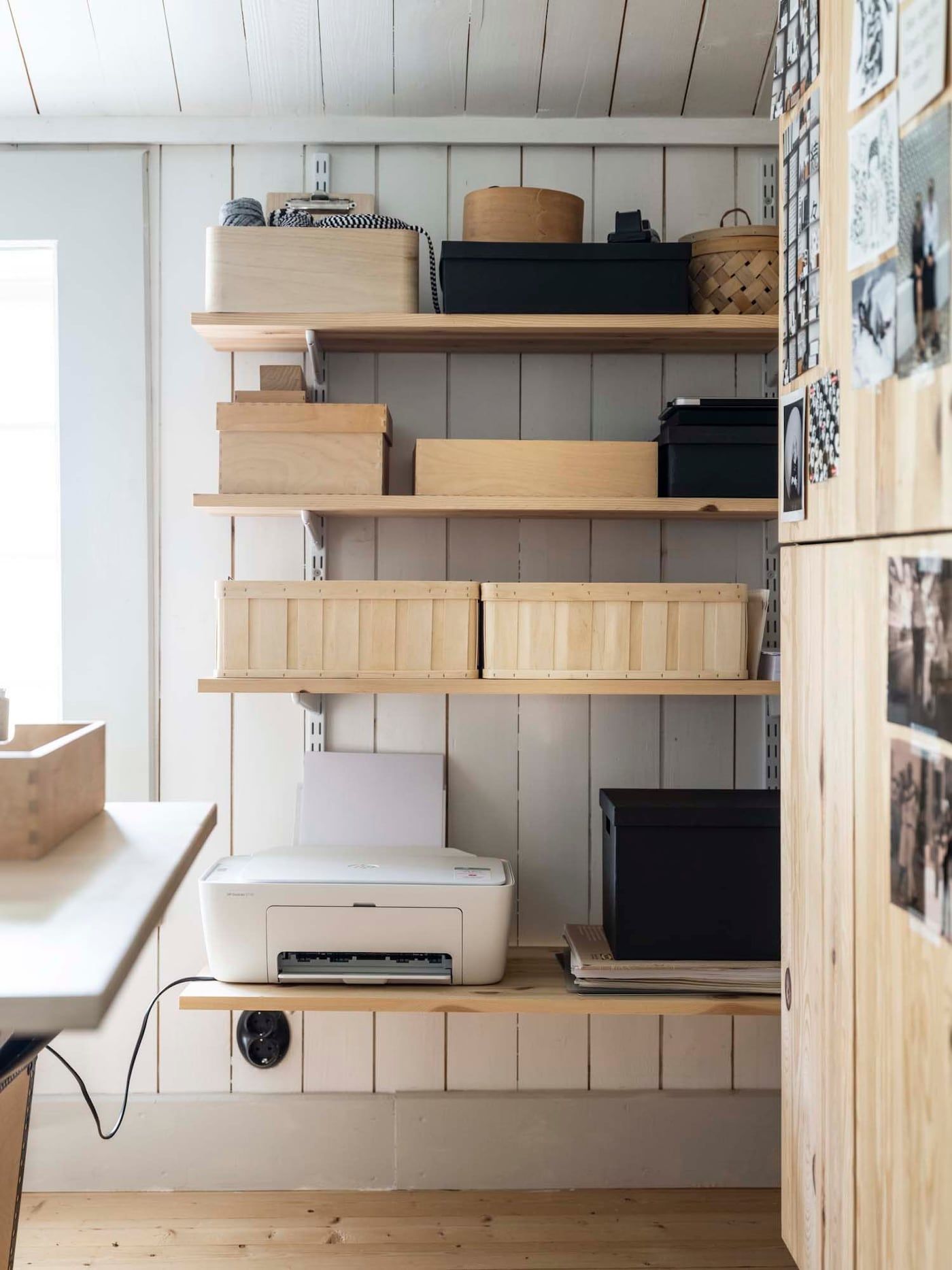 Wooden shelves storing a printer, storage boxes and other office supplies.