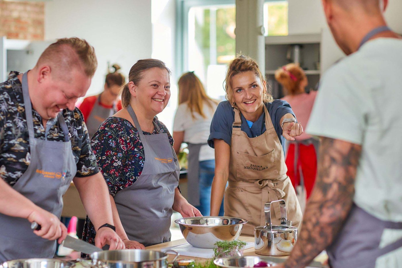A group of people talk and smile while preparing food.