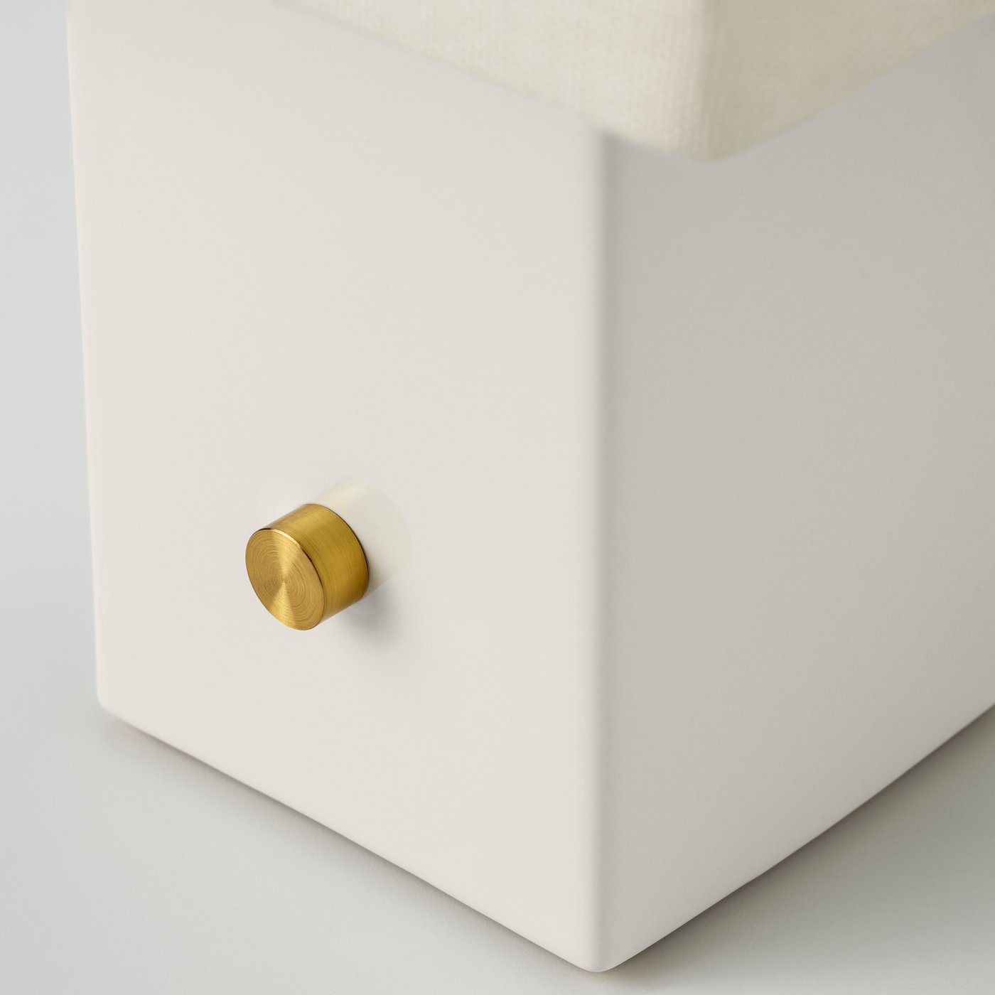 White ceramic lamp base with a round brass dimmer detail on the side.