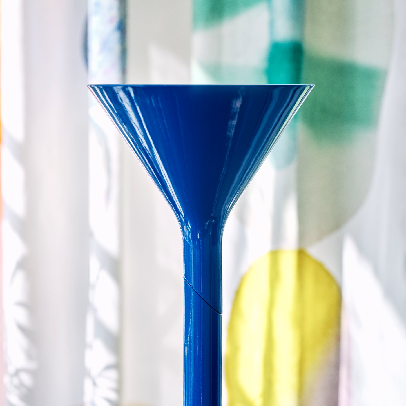 Close-up of a glossy blue cone-shaped lamp head against a softly patterned background.