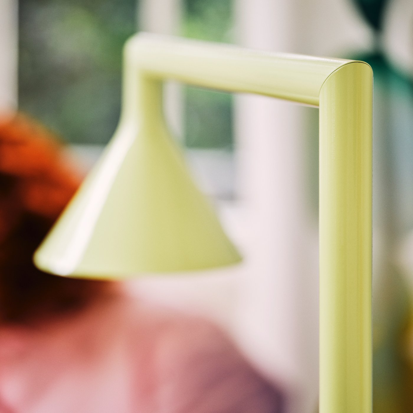 Close-up of a pale yellow floor lamp with a cone-shaped shade, softly blurred background.