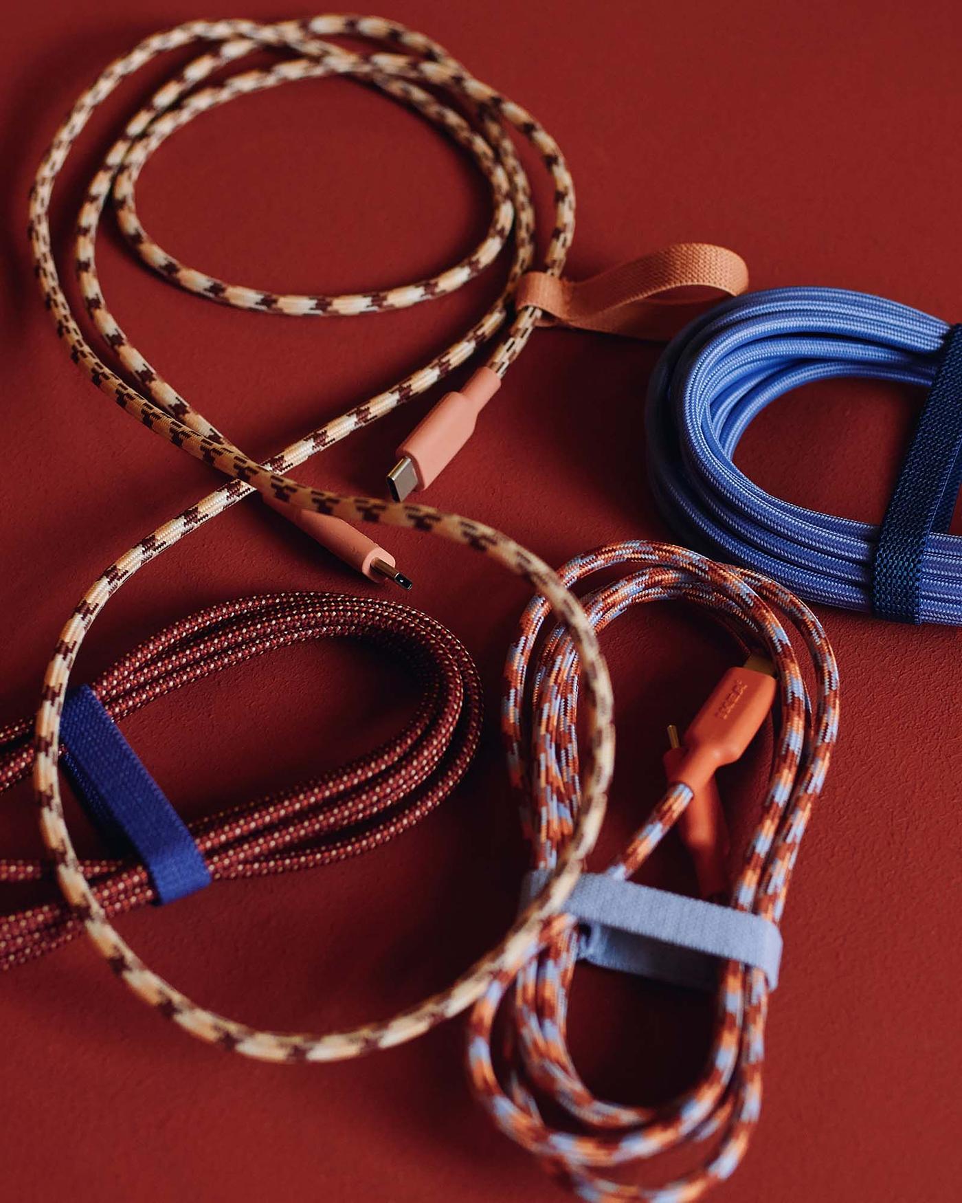 Bundles of colourful, patterned charging cables are placed on a burgundy backdrop.