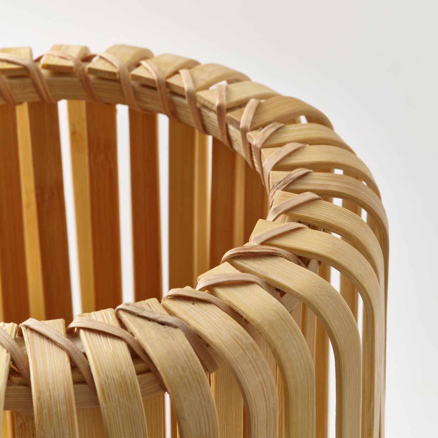 Close-up of a lampshade made from bent bamboo slats, showing crisscross weaving detail.