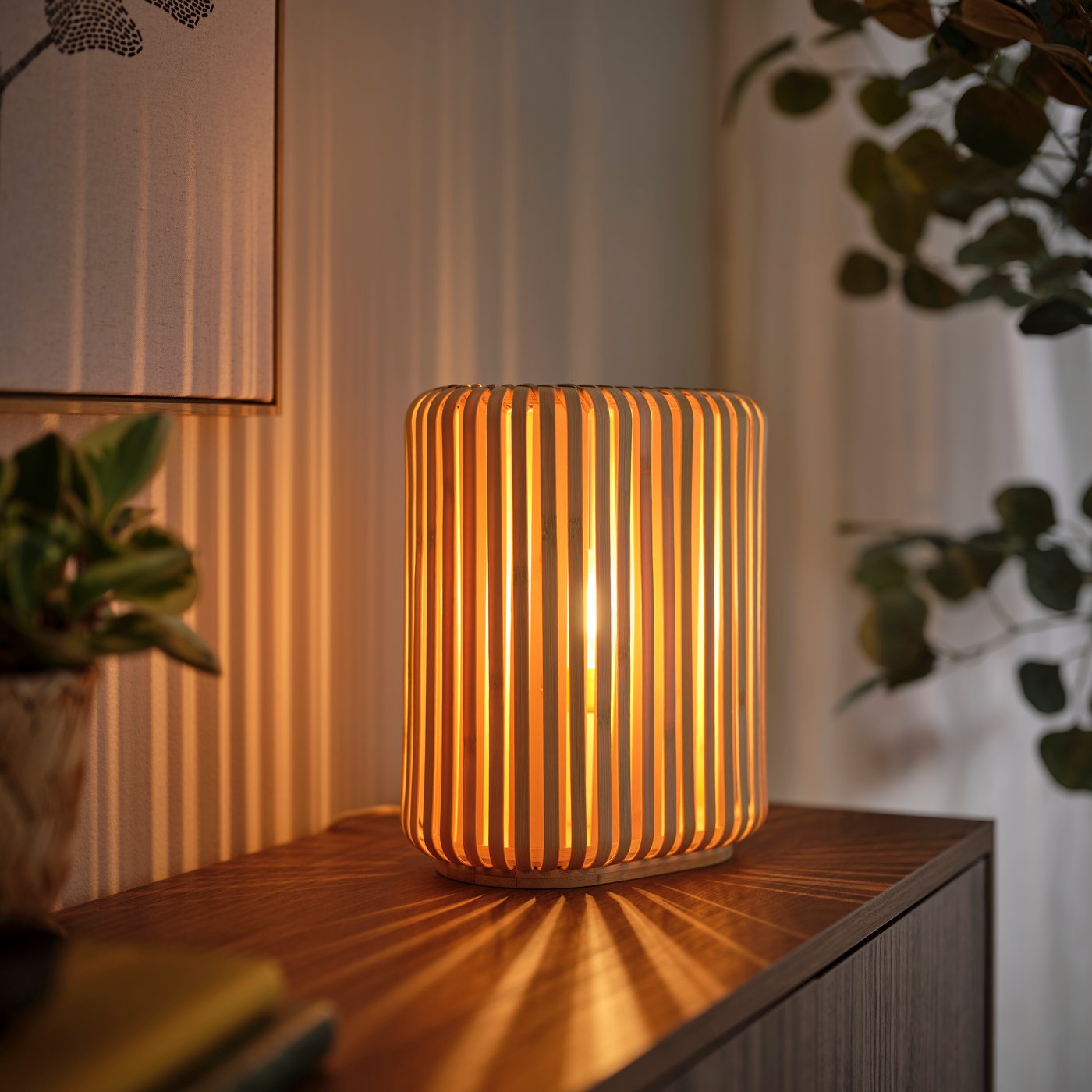 Close-up of the VARPTROSS table lamp with vertical bamboo slats casting warm light and soft shadow patterns on a wooden surface.