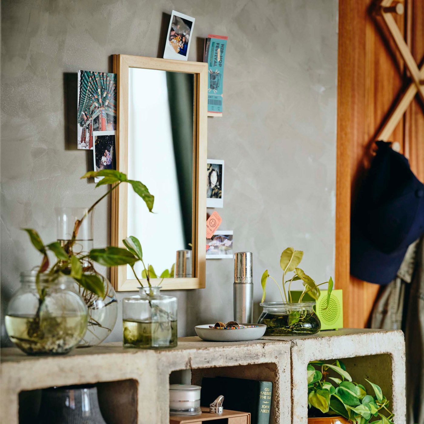 A mirror with photos attached hangs on a concrete wall.