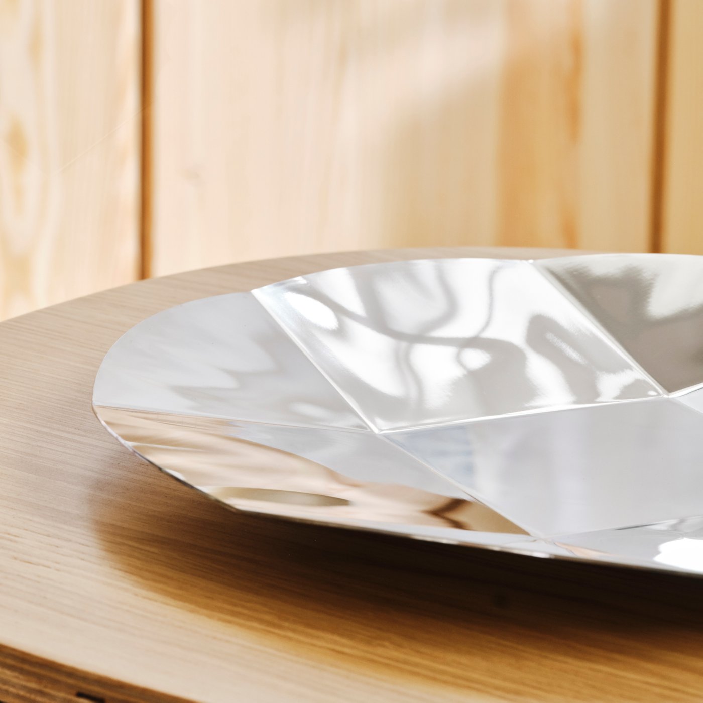 A round stainless steel platter with a faceted surface inspired by an Xbox controller D-pad.