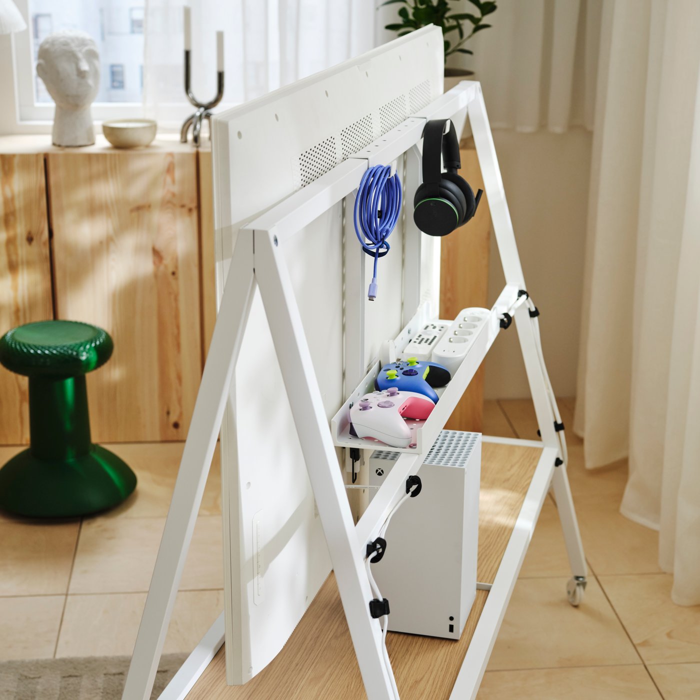 Rear view of a white YXSTABY TV stand with organised cables, controllers, headphones and gaming accessories.
