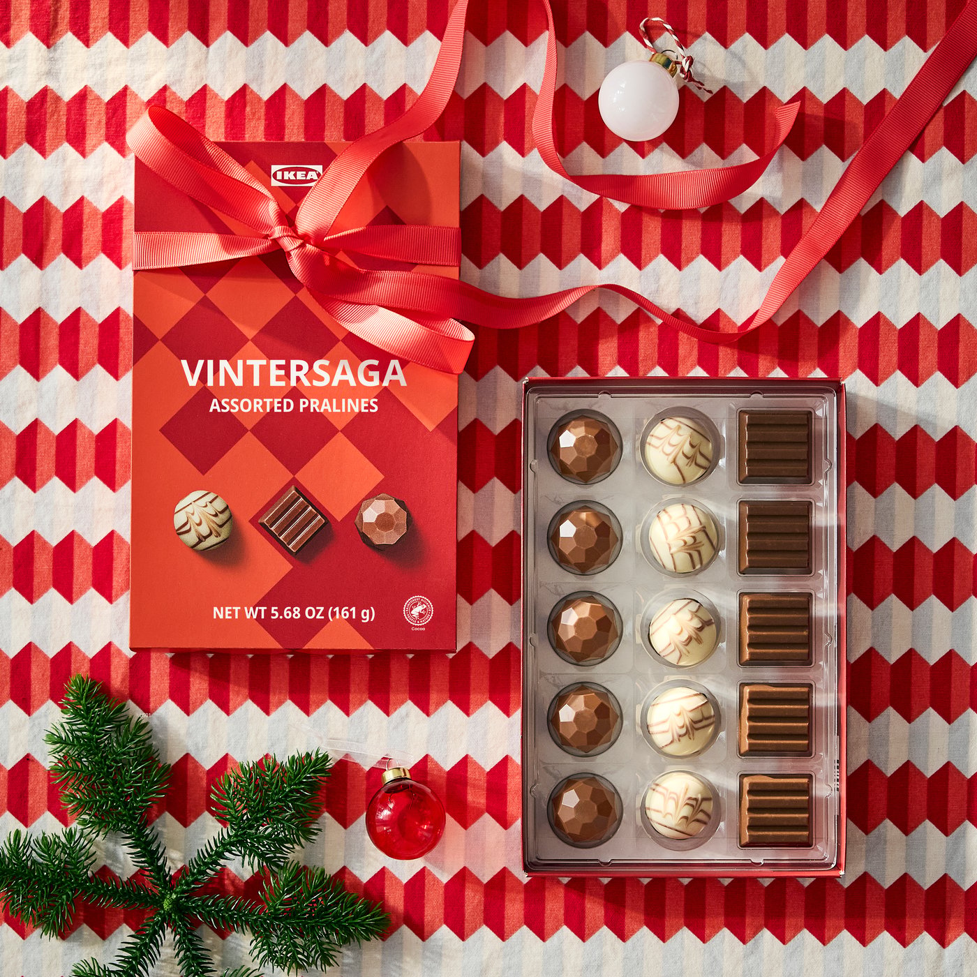 A gift box with sorted pralines displayed on festive wrapping paper.
