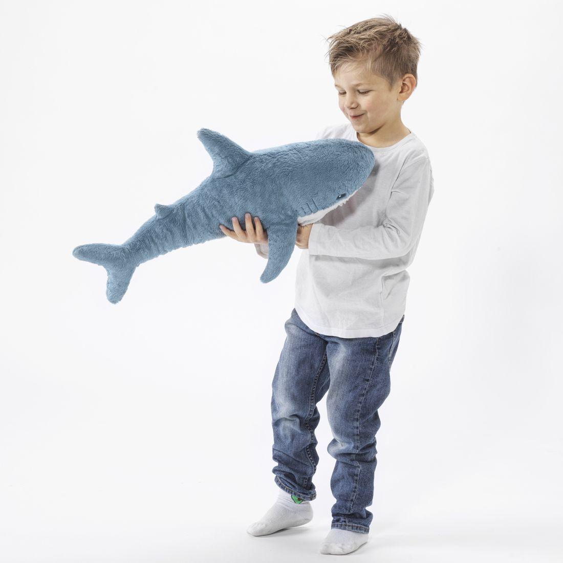 A small boy holding a soft toy shark from the IKEA BLÅVINGAD collection.