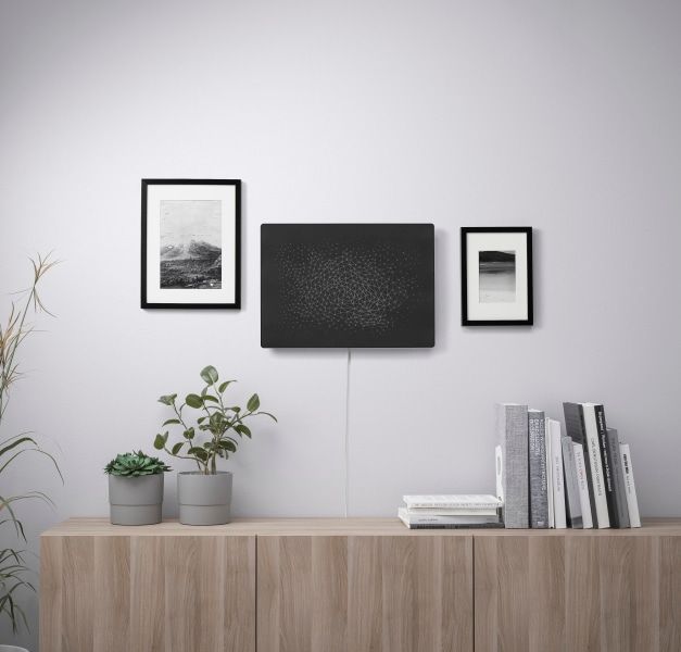 SYMFONISK Picture frame with Wi-Fi speaker on a wall above a media unit surrounded by two small picture frames.