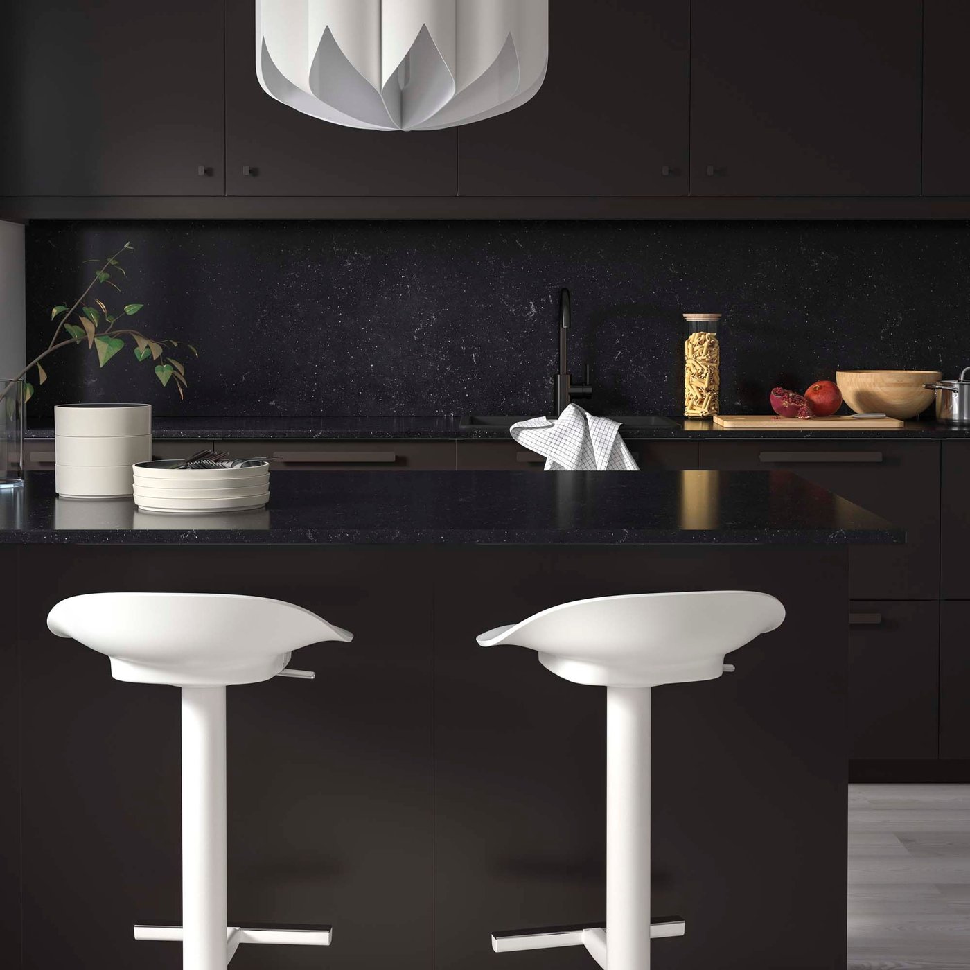 A black kitchen with black LOCKEBO worktops and white stools.