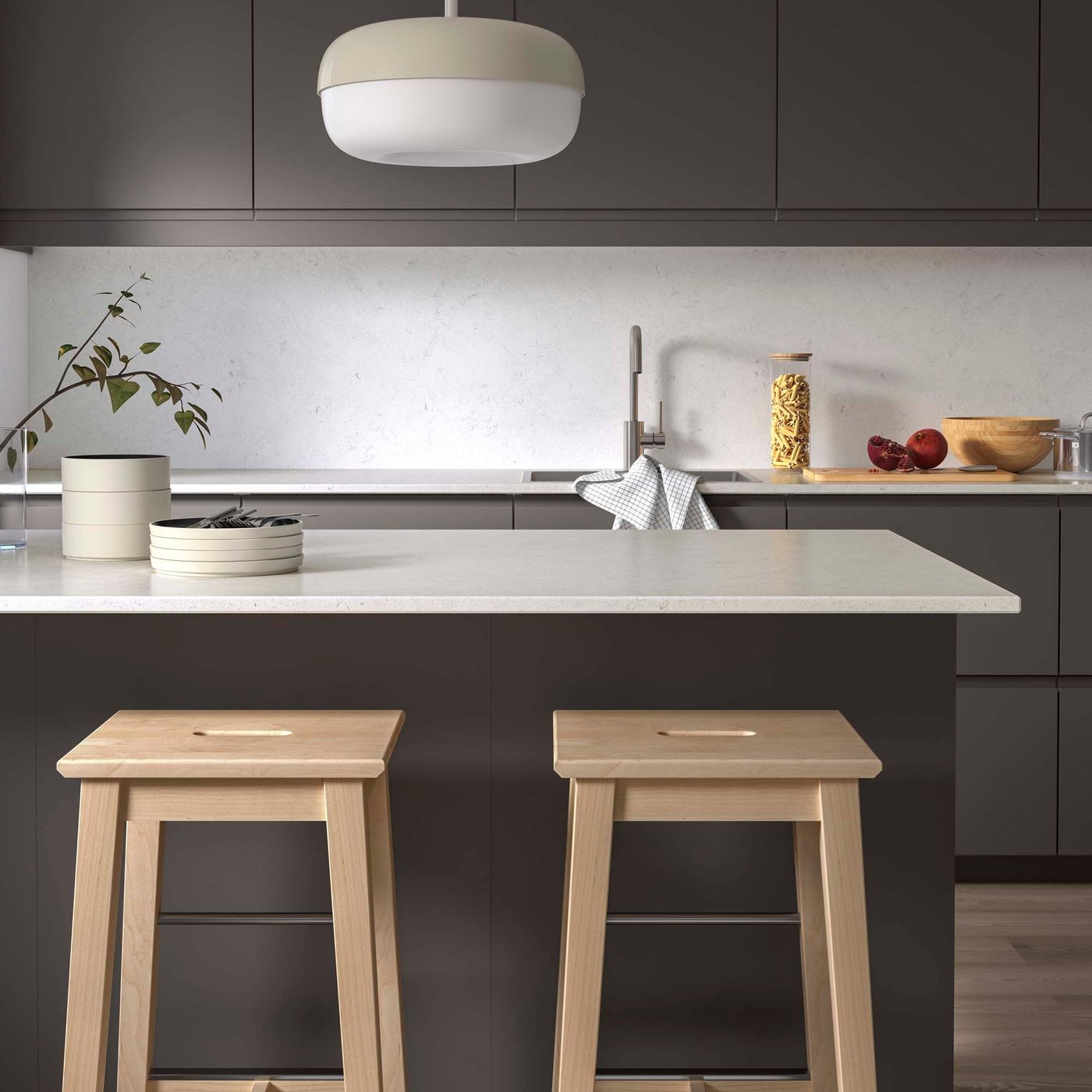 A kitchen with dark cabinets, light wooden stools and light LOCKEBO worktops.