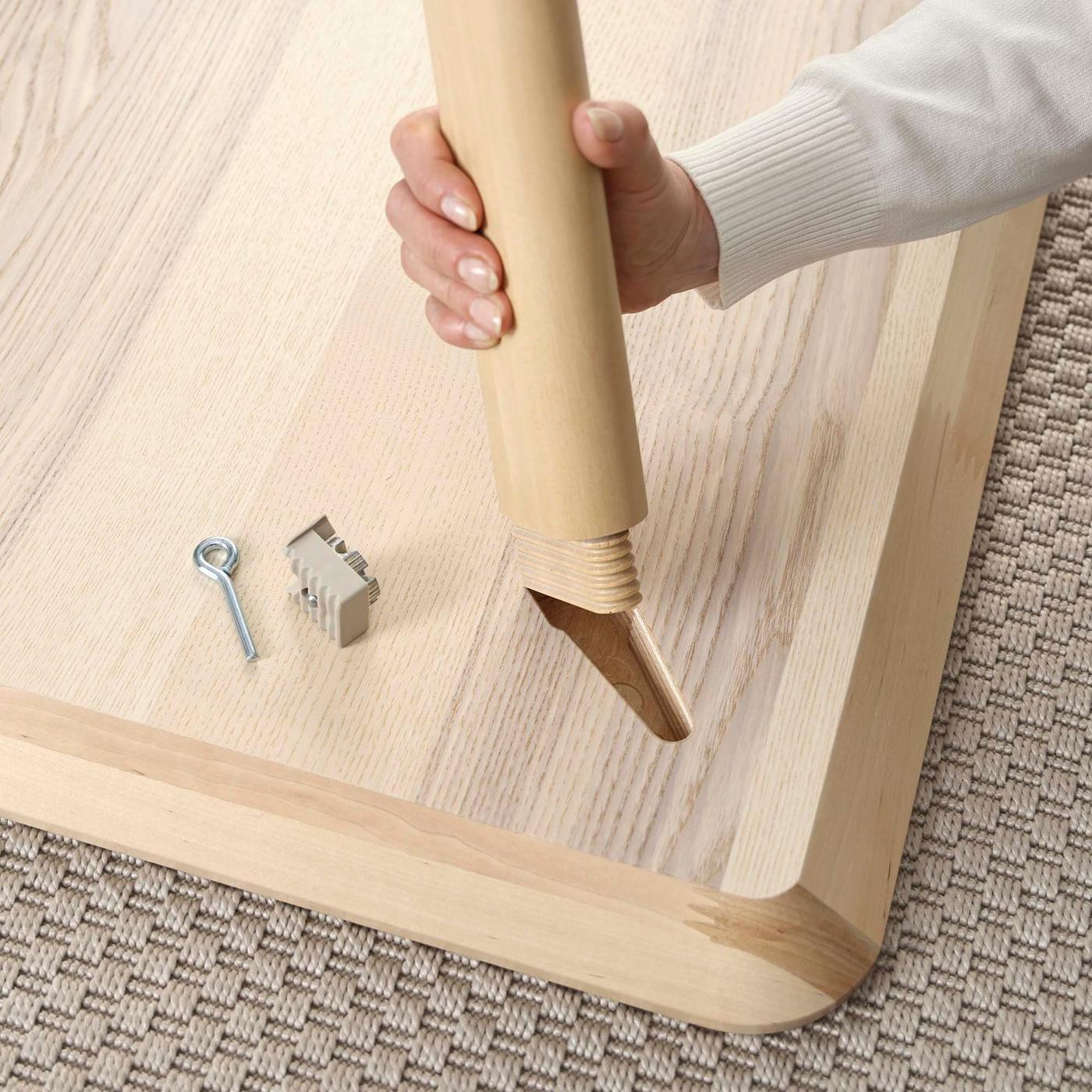 A person assembles a wooden table.