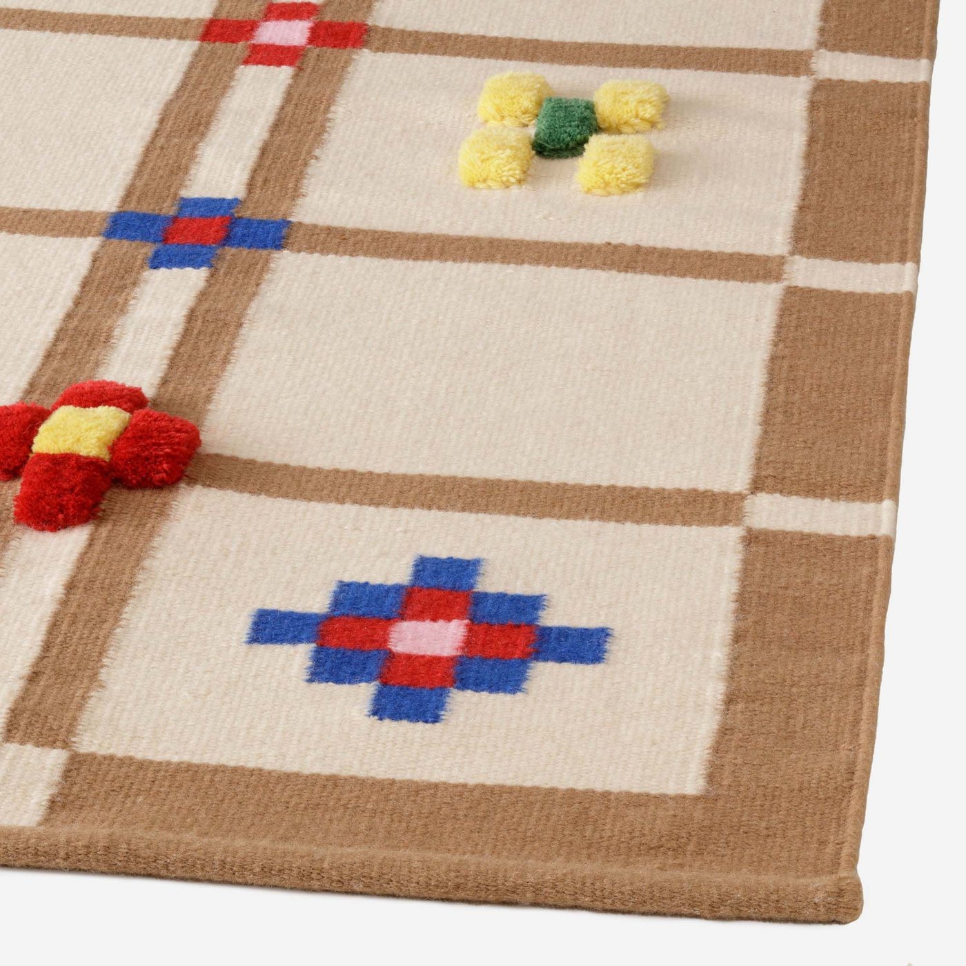 A close-up shot of a beige and brown check KNYLHAVREN rug, with coloured patterns inside some of the checks.