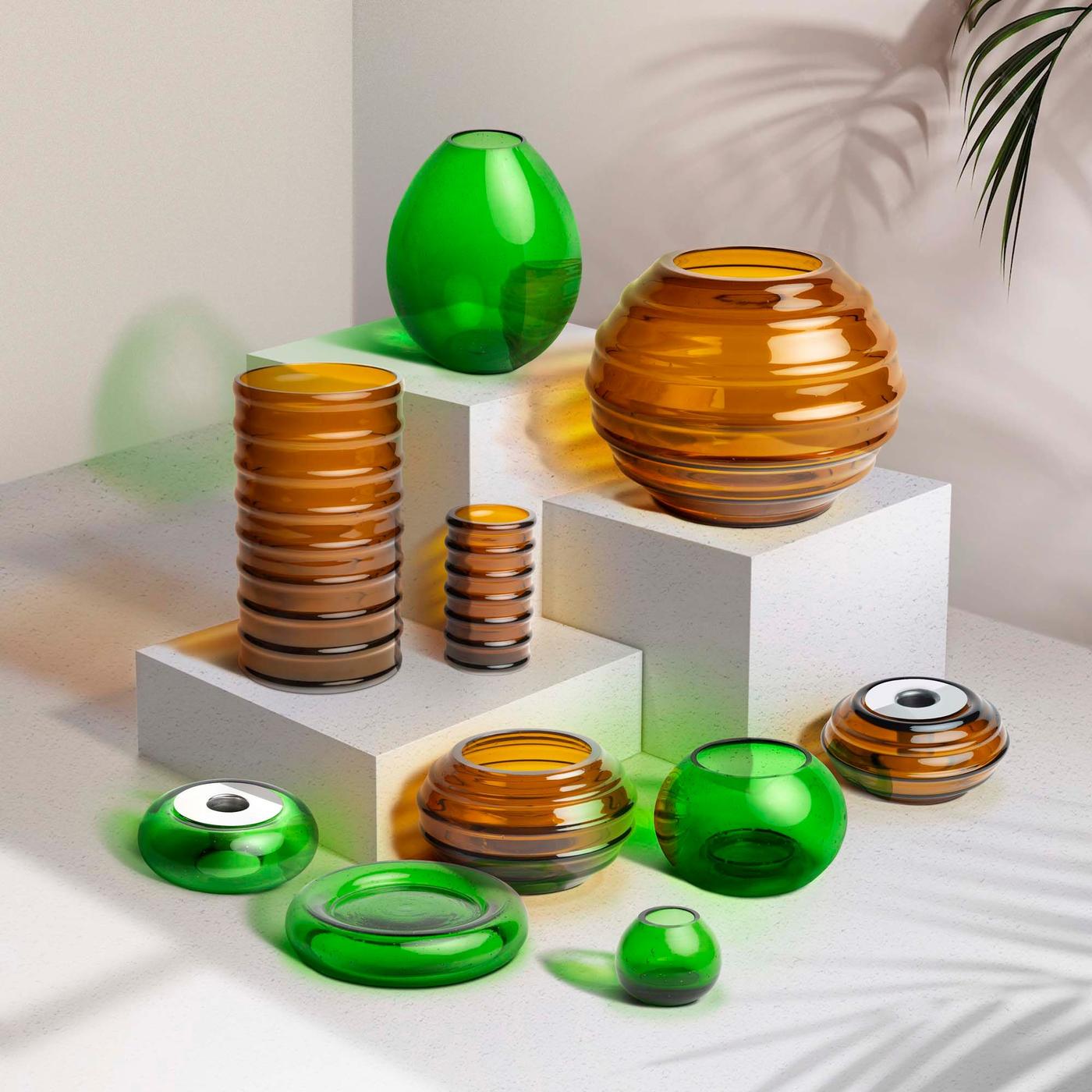 A collection of orange and green glass objects. Some are on podiums.