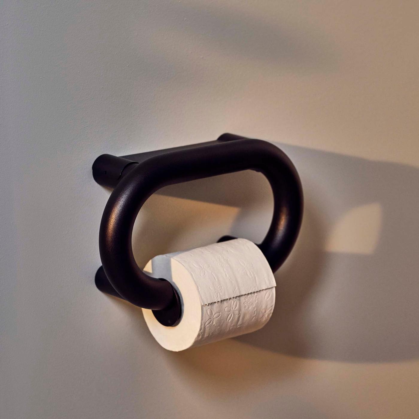 A toilet roll on an anthracite BÄSINGEN toilet roll holder attached to a grey-beige wall.