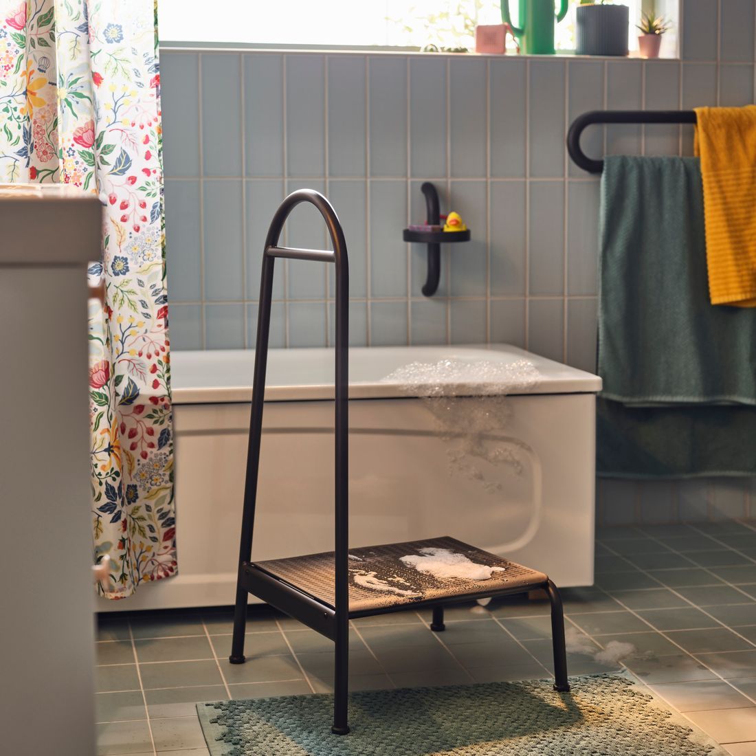 A bathroom with a bath tub and next to the bath tub you see one of the BÄSINGEN step stools with a rail.