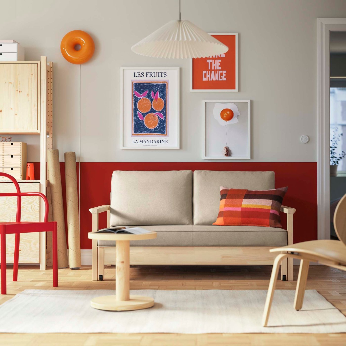 A beige sofa bed with a wood frame in a red and white living room with a gallery wall.