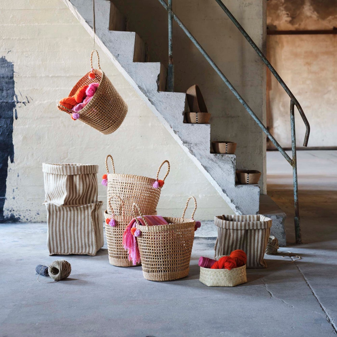 Baskets are stacked on the floor and hang in front of concrete stairs.