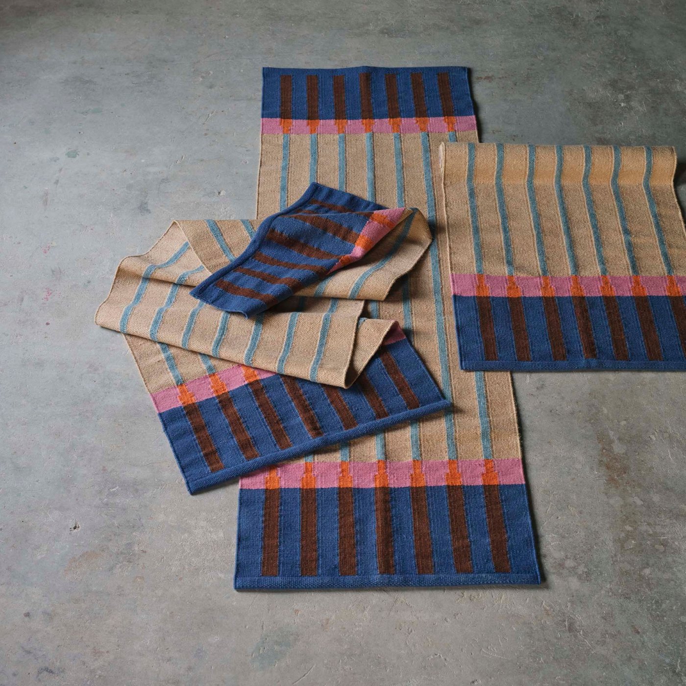 Striped coloured runners and place mats on a concrete floor.