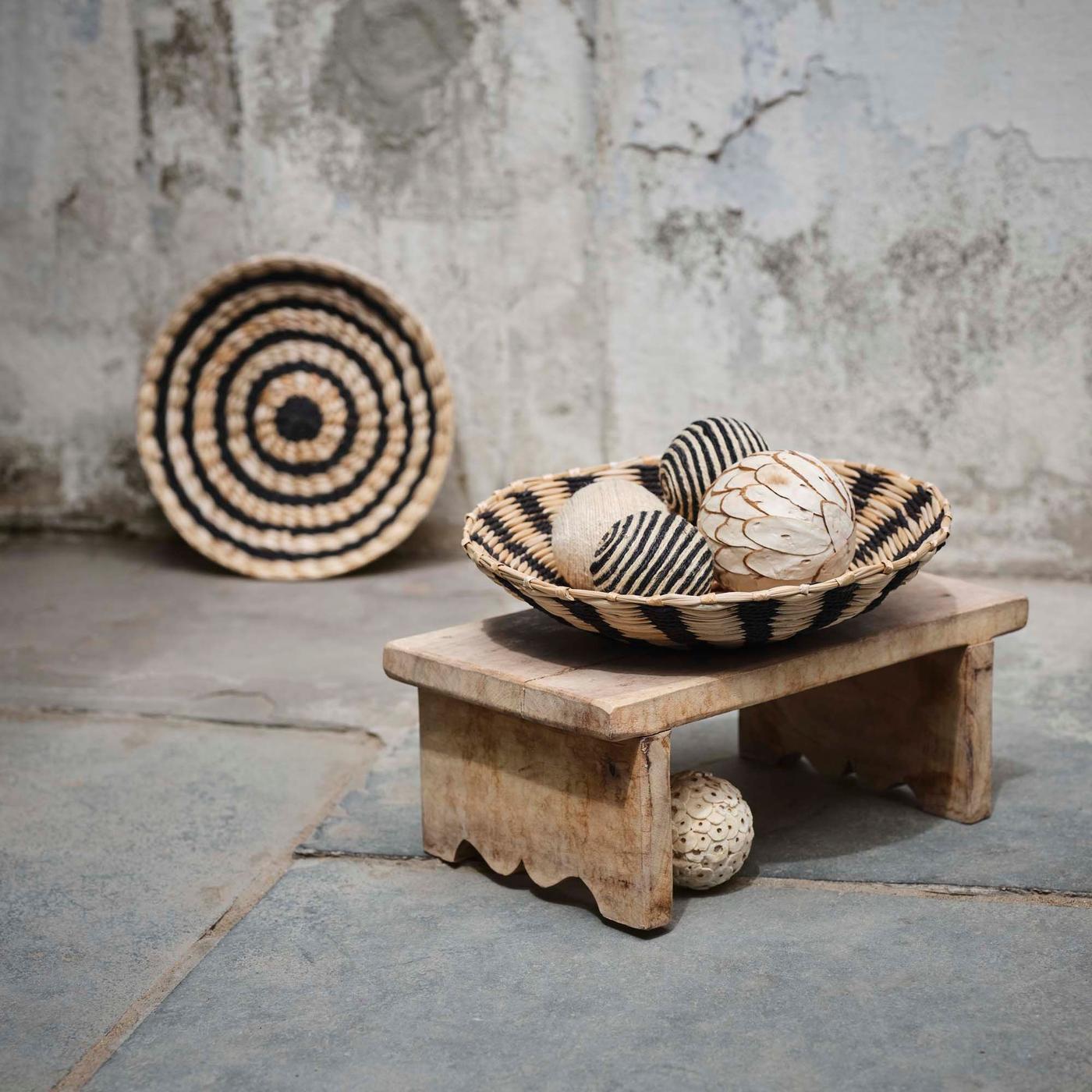 A basket leans against the wall, while another filled with balls sits on a wooden stool.