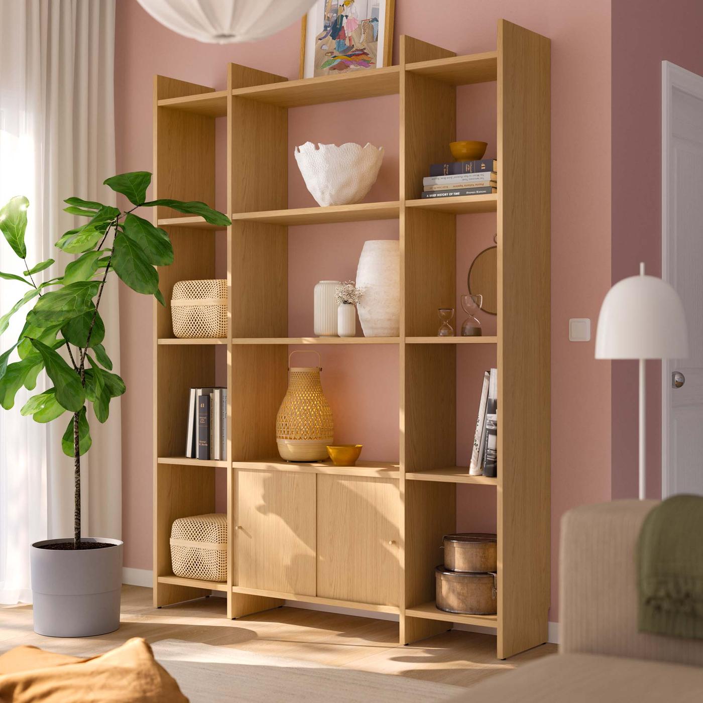 A LÅDMAKARE storage system filled with decorative objects in a pink room. The light shines through the window nearby, casting shadows.