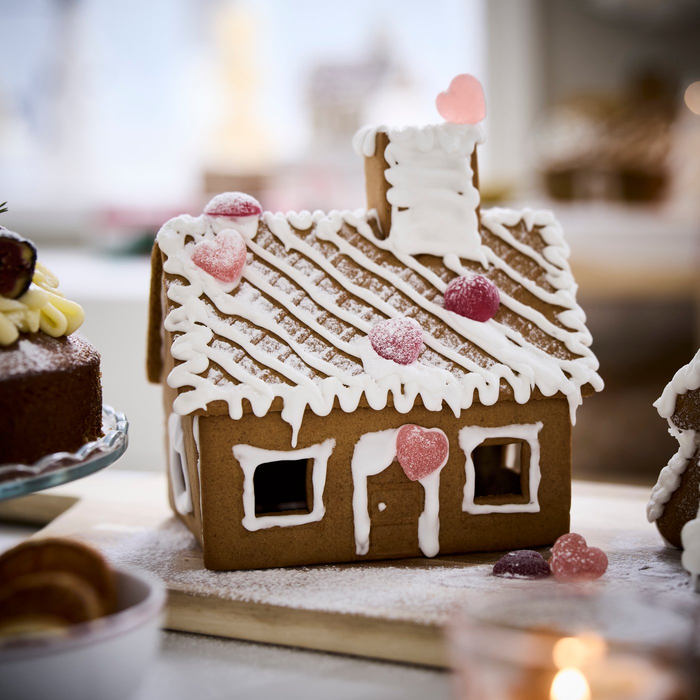 A gingerbread house decorated with icing, displayed on a festive table.