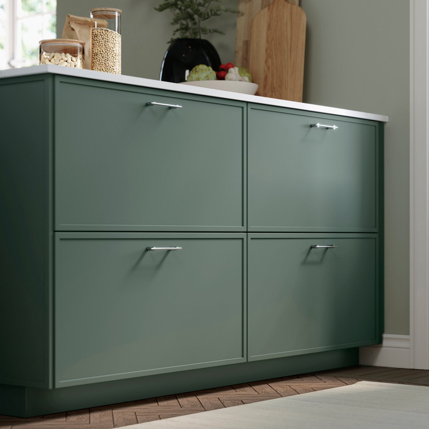 Close-up of a dark green kitchen unit with minimal style fronts and small metal handles in a kitchen.