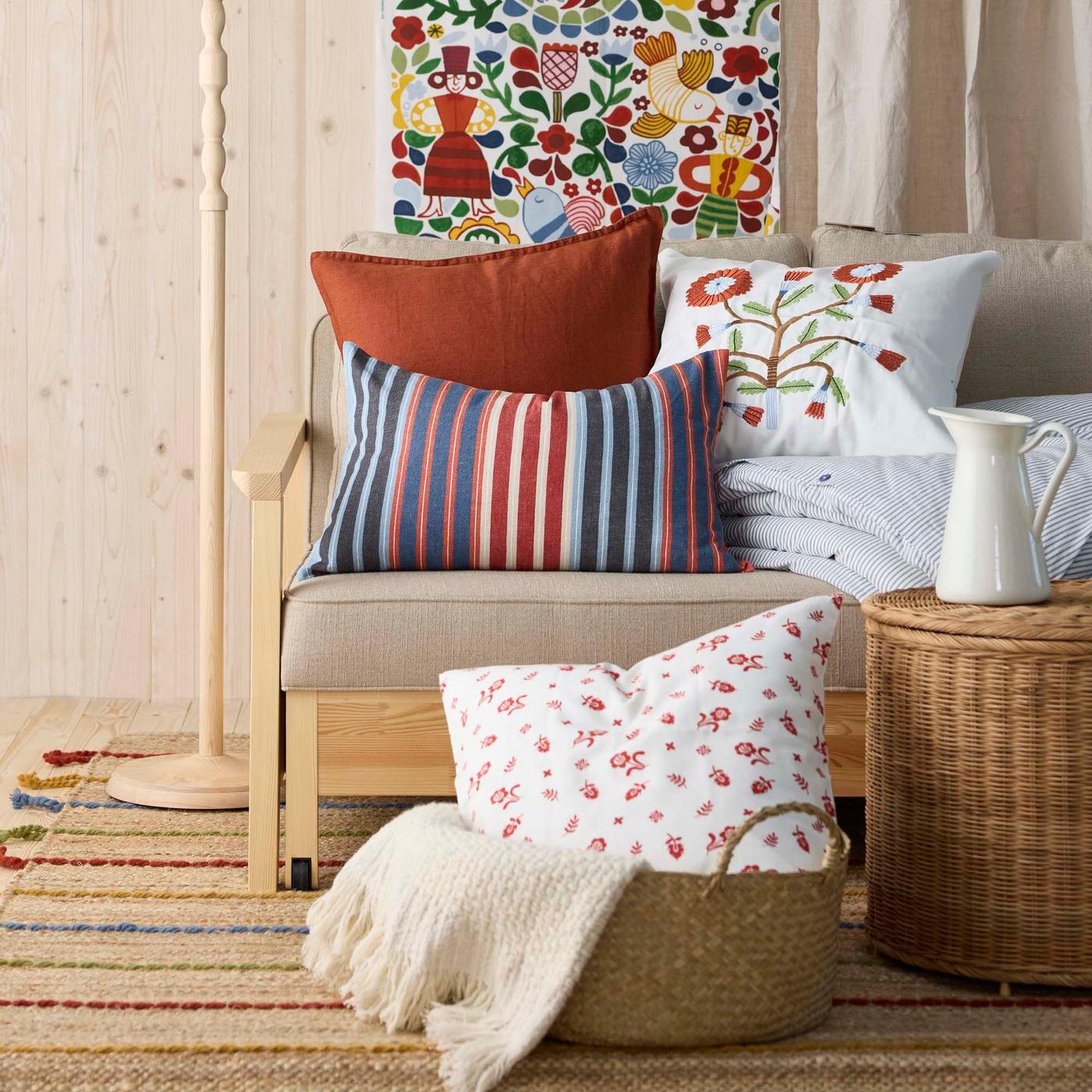 A sofa-bed loaded with cushions rests on a RAKLEV rug.